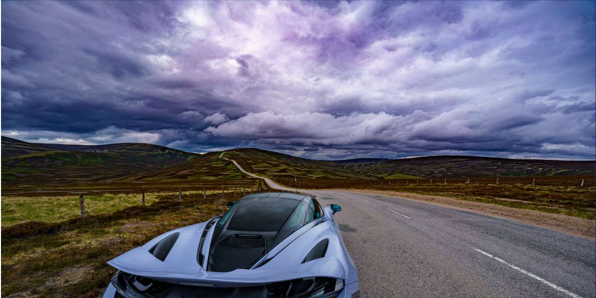 McLaren Supercar parked on the road on the edge of a mountainous area underneath a stormy sky