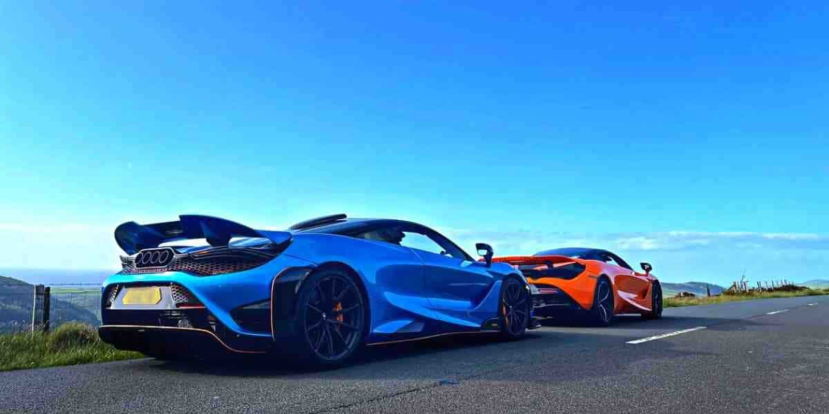 Two McLaren Supercars parked on the roadside under a blue sky