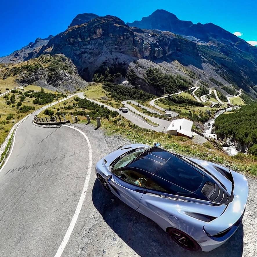 Mclaren 720s parked at the top of a road that cuts through a mountain range showing a Waynes World Of Wheels Dramatic Drive
