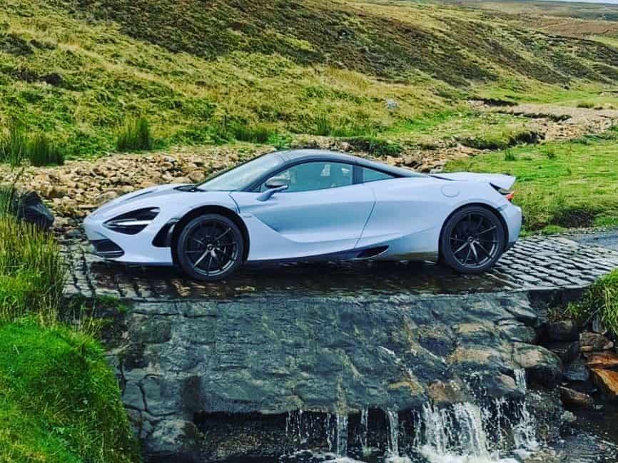 Mclaren 720s supercar parked in a ford in the countryside in Northumberland on The Pennine Way Super Car drive with Waynes World Of Wheels super car club