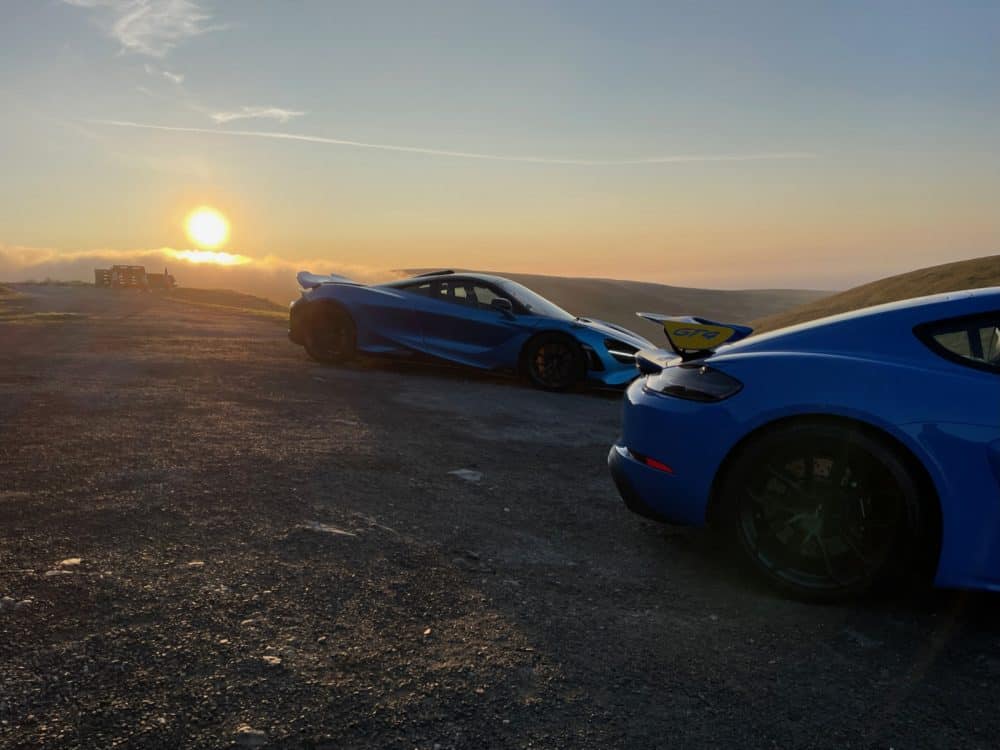 two supercars parked at sunset at the Isle Of Man with Waynes World Of Wheels