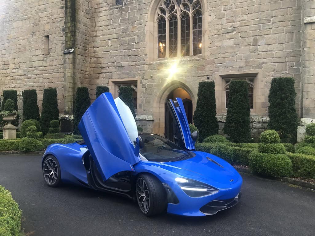 The Blue Mclaren Super Car leader of WWOW Supercar Club parked with both dorrs up and open in front of Langley Castle in Northumberland