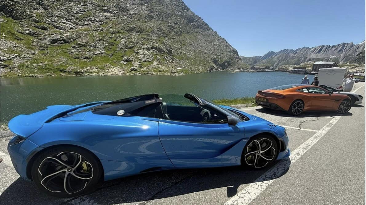 Blue McLaren 750s and orange Aston Martin DBS parked by the riverside in the Italian Dolomites while on a WWOW Supercar club tour